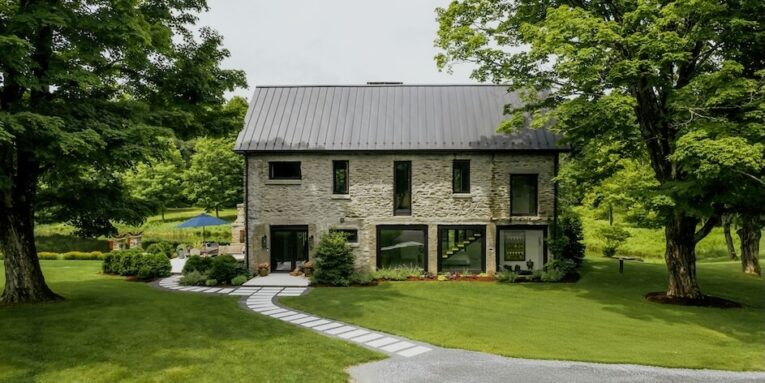 stone house with modern windows surrounded by trees FEATURED IMAGE