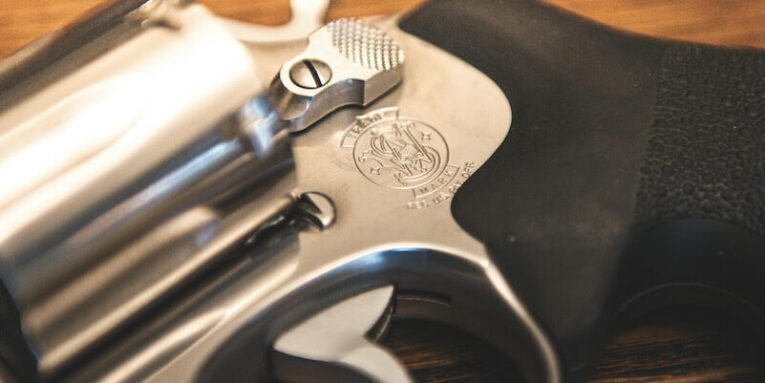 stainless steel revolver with black grip and wooden background FEATURED IMAGE