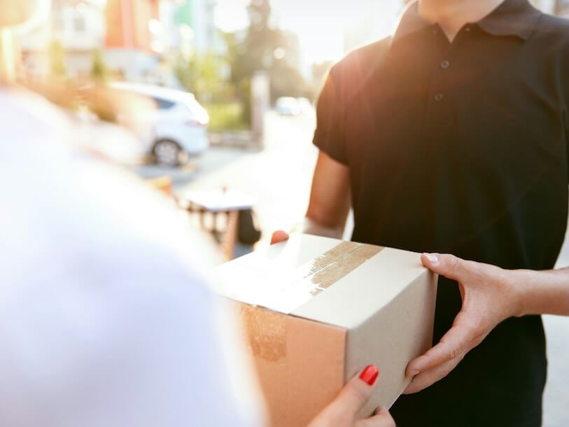 courier delivery service closeup of womans hands receiving package from delivery man high resolution