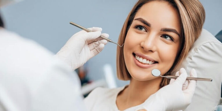 good looking woman with short hair sit in dental office and look at doctor with confidence she has perfect smile professional doctor of clinic use special sterilized medical instruments FEATURED IMAGE
