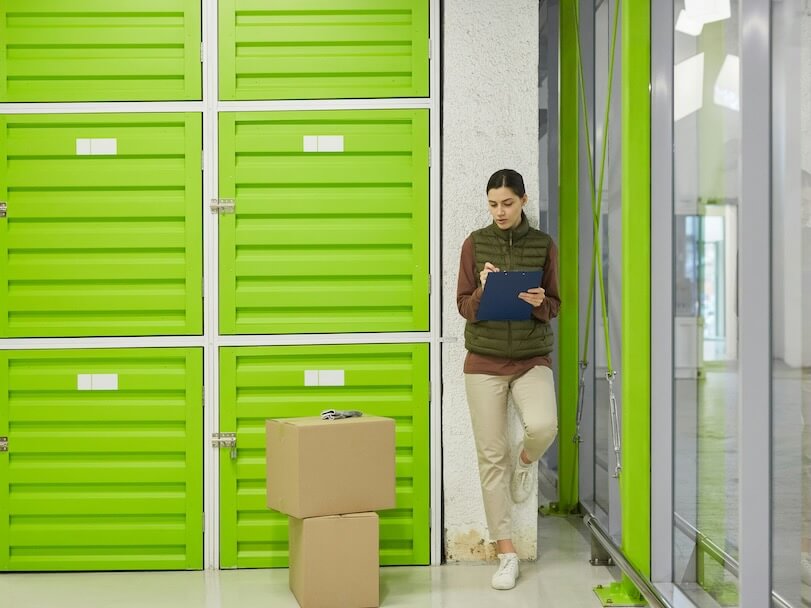 young worker making notes in document she registrating parcels before delivery in warehouse