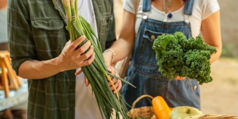 a man and a woman standing next to a basket of vegetables FEATURED IMAGE