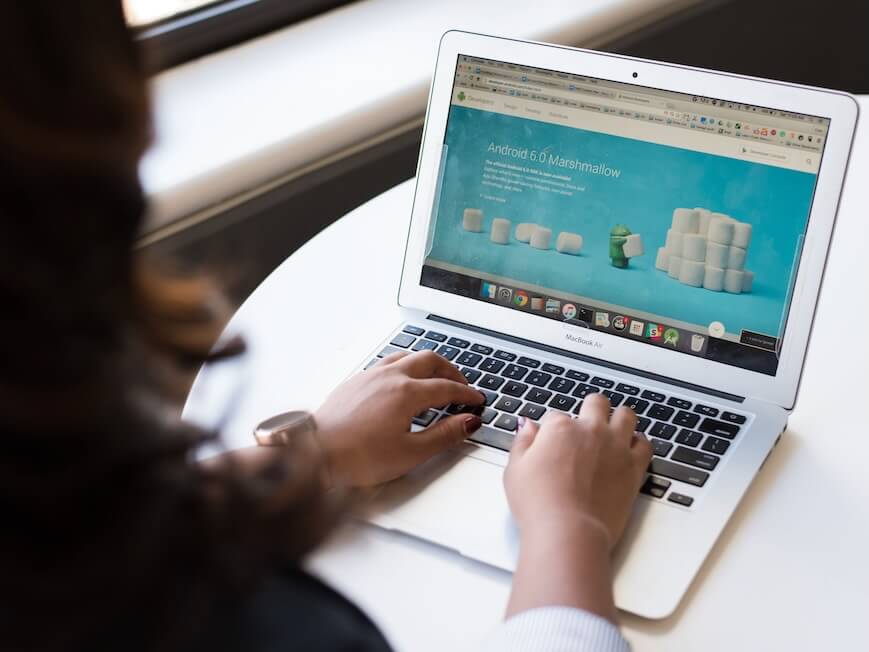 Businesswoman working on laptop with Android 6.0 Marshmallow webpage open.
