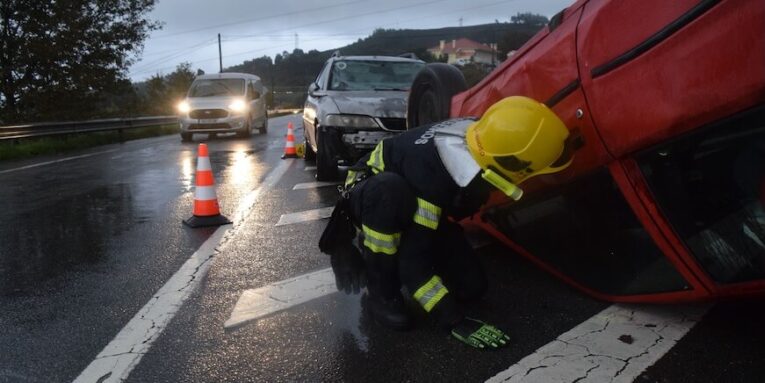 Firefighter attending to an overturned car on a rainy road in Póvoa de Lanhoso, Braga, Portugal - FEATURED IMAGE