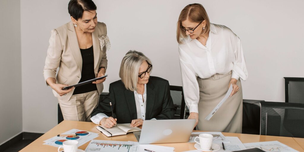 Three businesswomen discussing documents during a meeting in a modern office setting FEATURED IMAGE