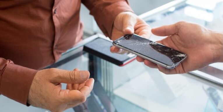 a couple of people that are looking at a cell phone FEATURED IMAGE