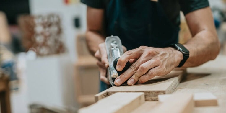 a man working on a piece of wood FEATURED IMAGE