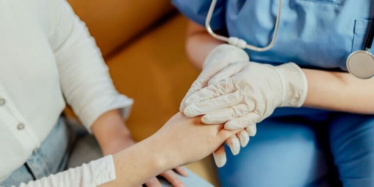 a nurse holding the hand of a patient FEATURED IMAGE