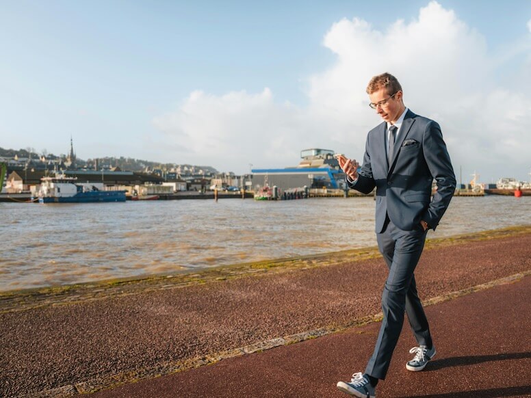 a man standing on a sidewalk near a body of water