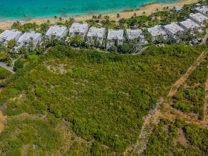 green land white coastal buildings sandy beach and turquoise ocean