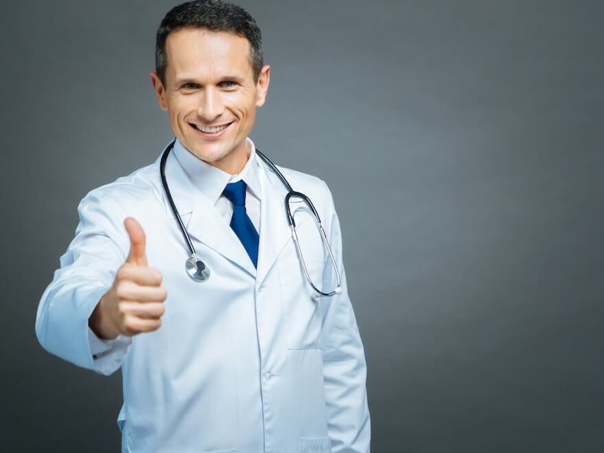 everything is cool waist up shot of a cheerful male doctor looking into the camera with a cheerful smile on his face while standing straight and showing a thumbs up