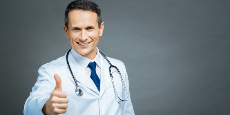 everything is cool waist up shot of a cheerful male doctor looking into the camera with a cheerful smile on his face while standing straight and showing a thumbs up FEATURED IMAGE