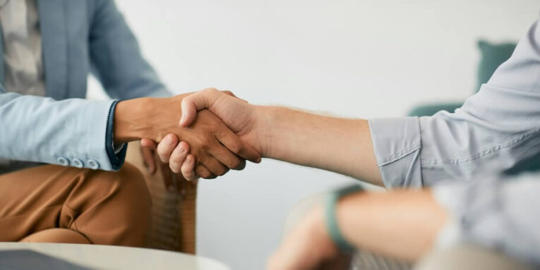 close up of coworkers shaking hands during business meeting in the office FEATURED IMAGE