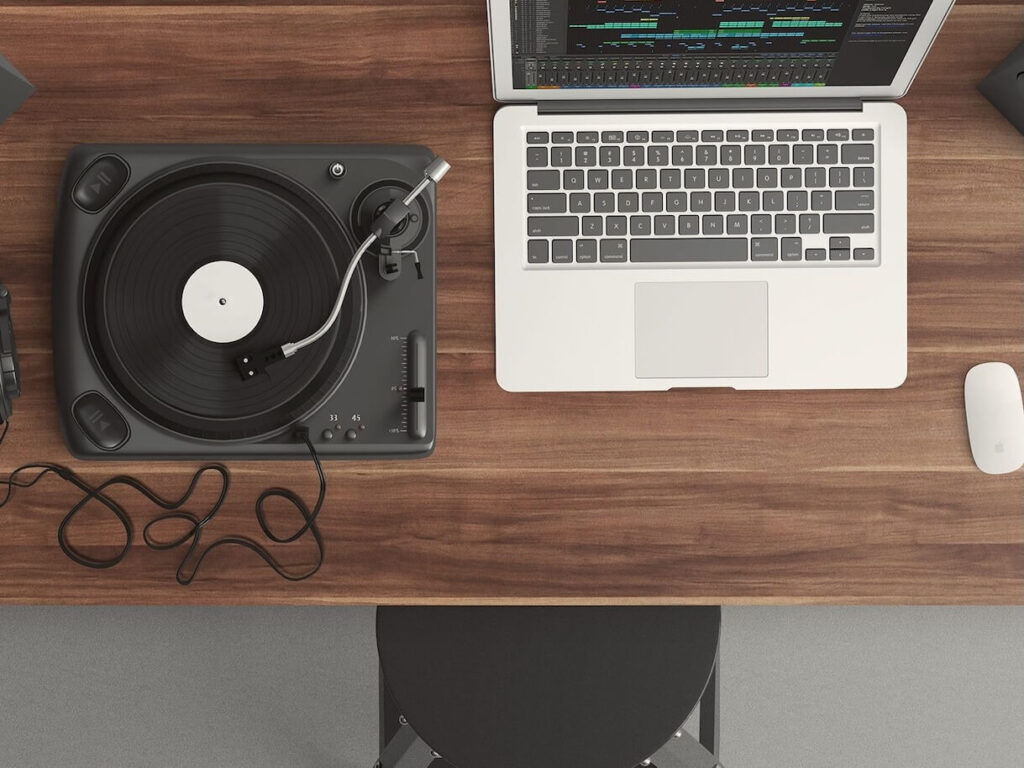Top view of a music production desk with a laptop and turntable setup for modern audio production.
