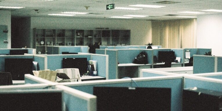 Spacious office floor with rows of empty cubicles and computer monitors FEATURED IMAGE