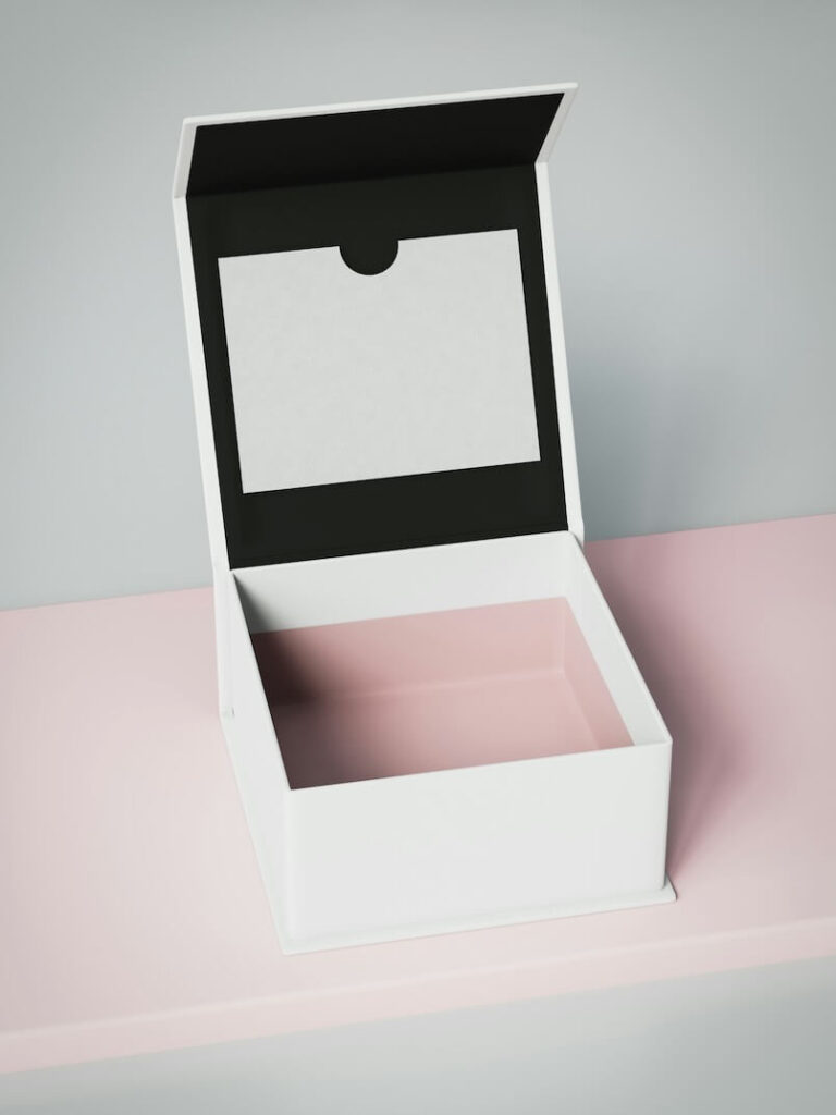 a white box with a black lid on a pink surface 