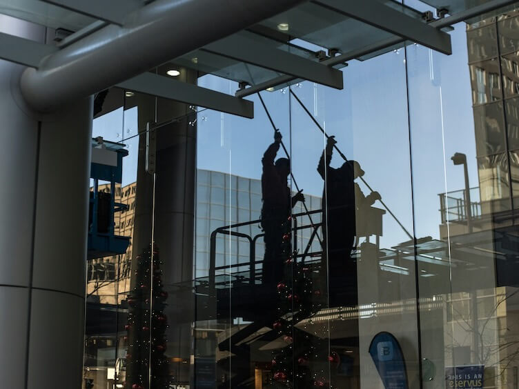 utility man standing in scissor platform cleaning glass window