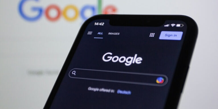a close up of a cell phone with the google logo in the background FEATURED IMAGE