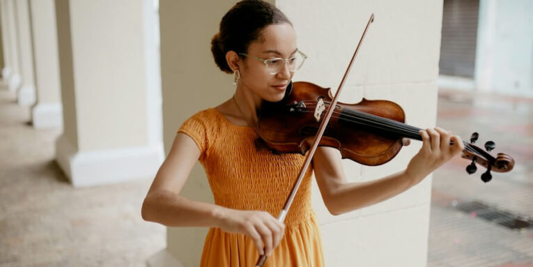 a woman in an orange dress playing a violin FEATURED IMAGE