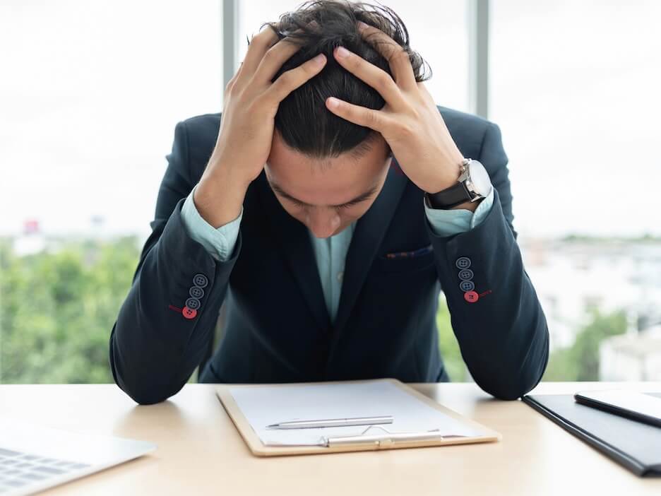 stressed businessman is holding his head with his hands while working at the office