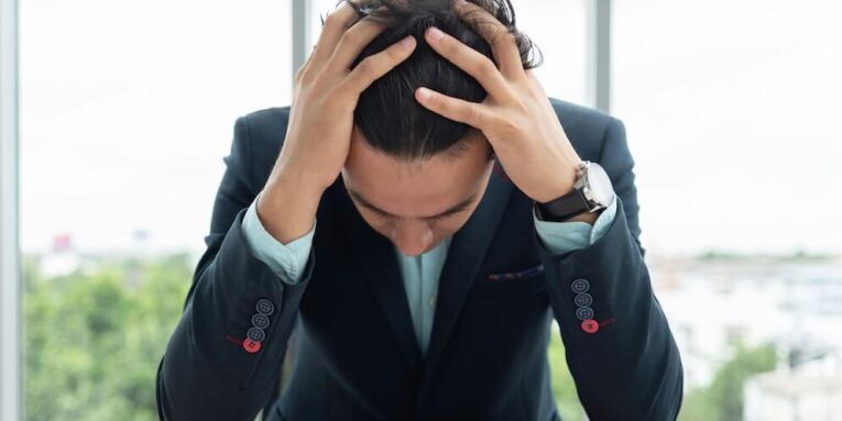 stressed businessman is holding his head with his hands while working at the office FEATURED IMAGE