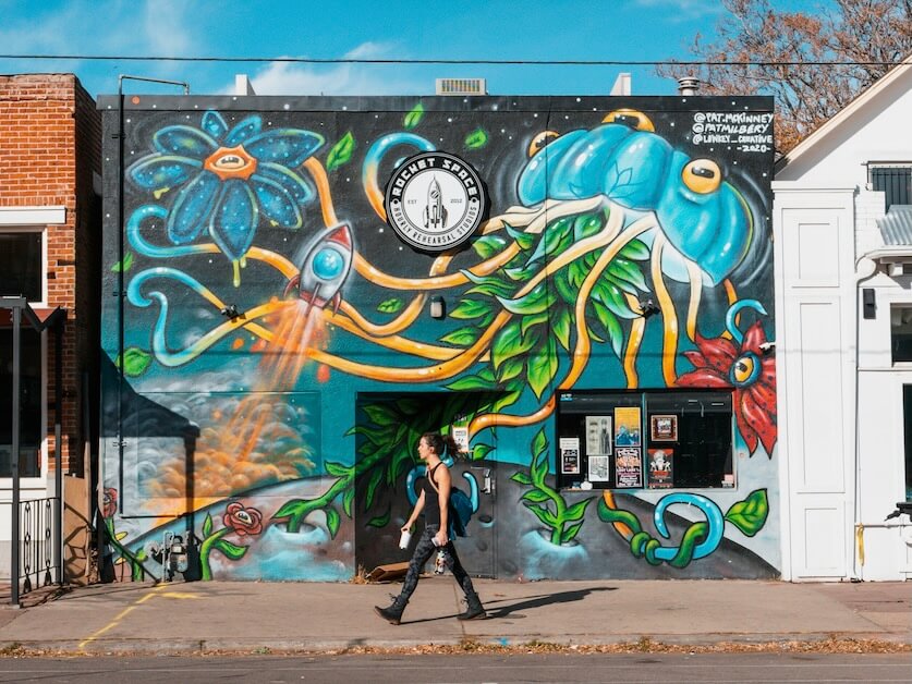 a person walking past a building with a mural on it