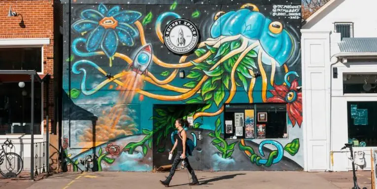 a person walking past a building with a mural on it FEATURED IMAGE