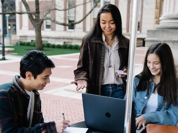 Group of university students collaborating and studying together in an outdoor setting.