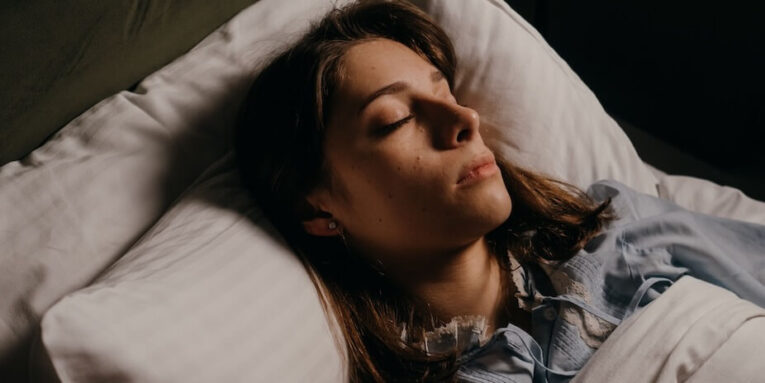 Woman sleeping peacefully in bed, highlighting comfort and serenity in a cozy bedroom setting FEATURED IMAGE