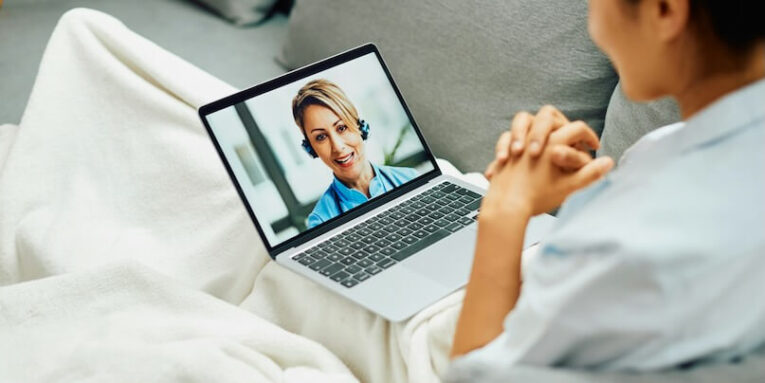 smiling female doctor having video call with patient who is calling her from home via laptop FEATURED IMAGE