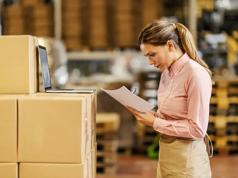a female food factory worker standing in warehouse and checking on goods