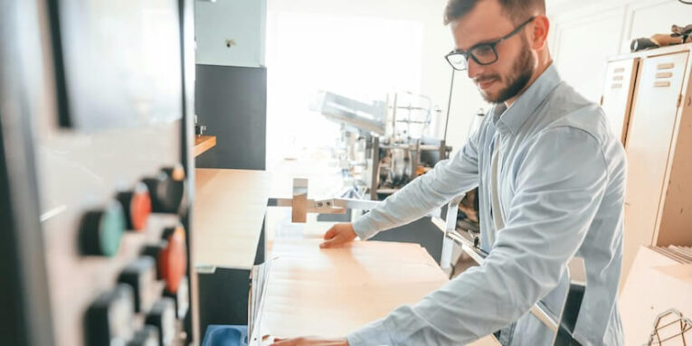 working with wooden sheets man in print house that in white clothes is indoors FEATURED IMAGE