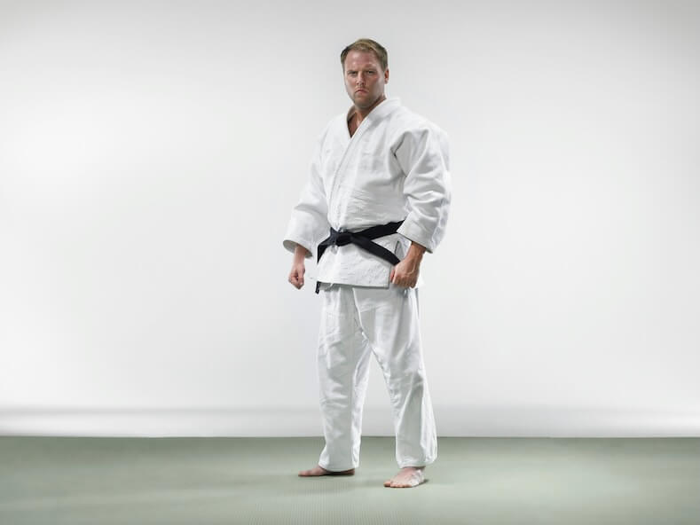 a man in a white kimono standing with his hands in his pockets