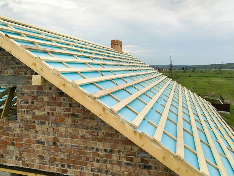 aerial view of a brick house with wooden roof frame under construction