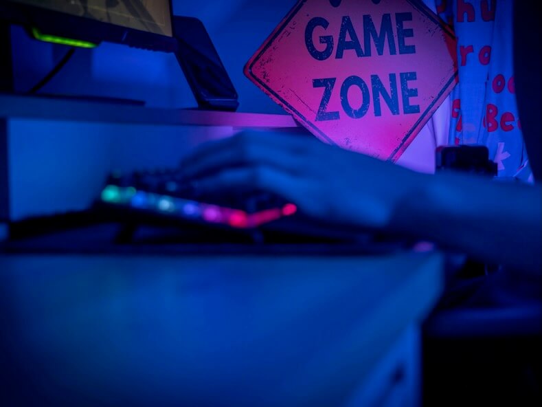 a person typing on a keyboard in front of a game zone sign
