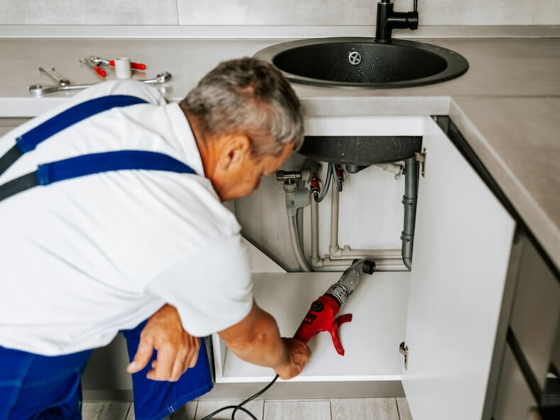 a plumber is working under a kitchen sink