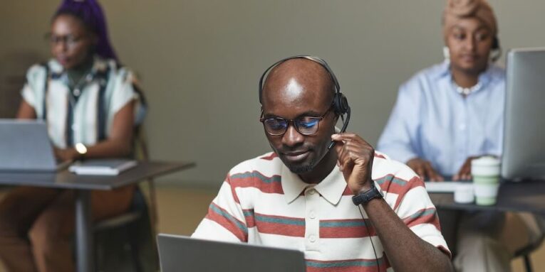 A focused call center team working on laptops and wearing headsets in an office setting FEATURED IMAGE