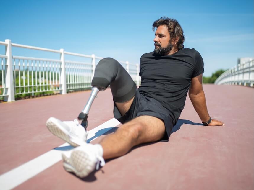 Man with prosthetic leg sitting on outdoor track, embodying resilience and active lifestyle.